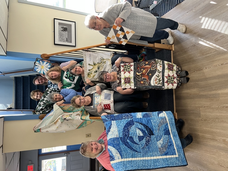 Quilting retreat group proudly displaying their creations