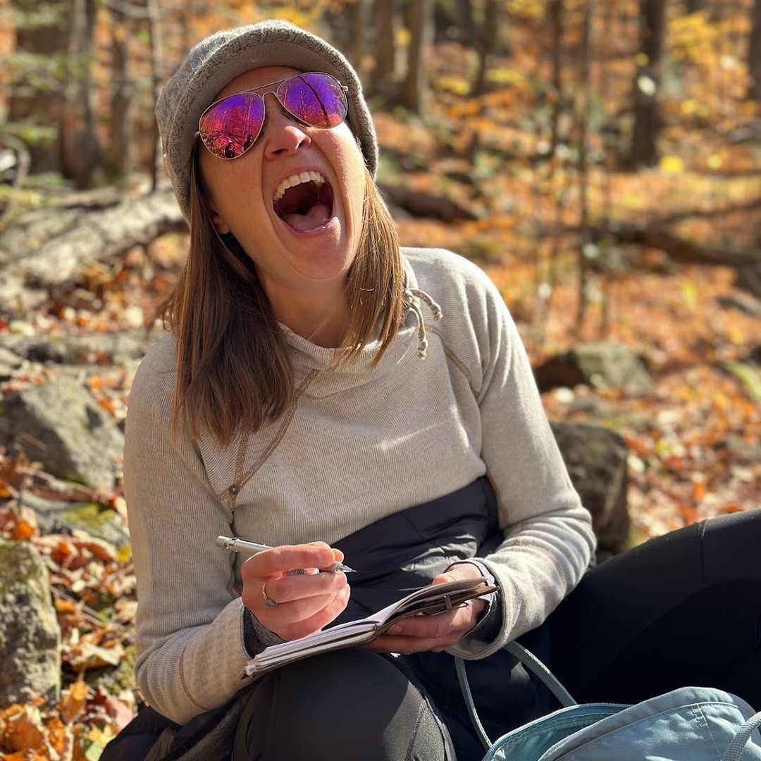 Megan laughs while sketching in a notebook during a hike